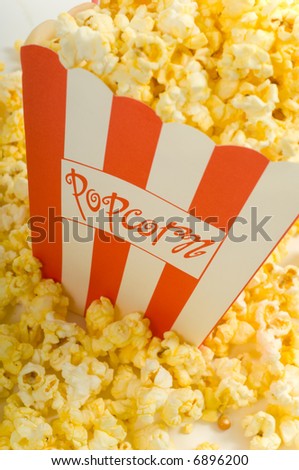 Movie popcorn on white background with red striped box and freshly popped popcorn
