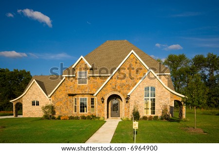 A beautiful two story home with a green lawn and a beutiful blue sky.  Real estate concept