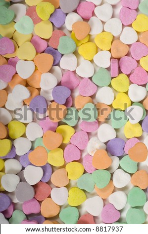 Pastel colored conversation hearts with no text, background with copy space