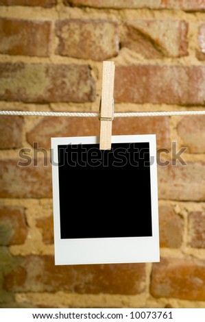 Instant transfer images or instant photos on a clotheline in front of a brick wall with clipping path for image area