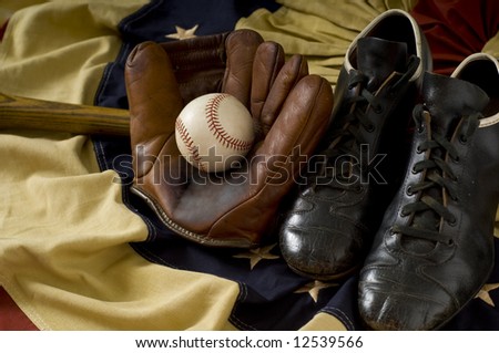 Vintage, antique baseball gear on vintage American flag bunting, inlcuding a baseball mitt or glove, baseball shoes or cleats, a baseball bat and a baseball. sports background