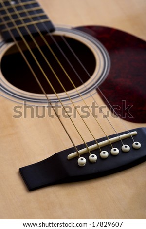 A 6-string acoustic guitar background with focus on the bridge, with copy space
