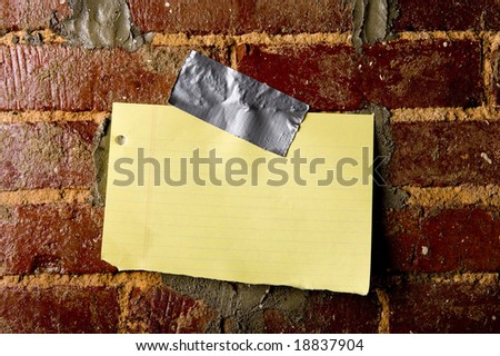 A blank sheet of paper taped to a brick wall with copy space