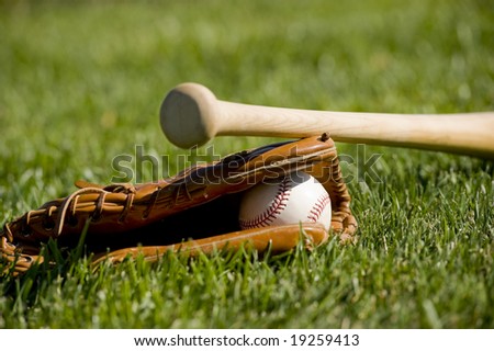 A baseball field with a leather baseball glove, a ball and a wooden bat