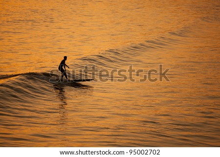 Single surfer at sunset on a calm ocean
