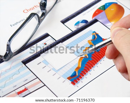 Male hand with pen on the investment charts with glasses