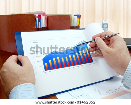 Male hand with pen on the investment chart.