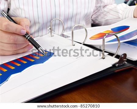 Businesswoman hand with pen on the investment chart.
