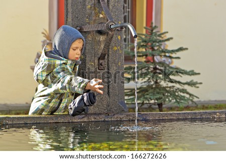 Cute three years old boy playing with water