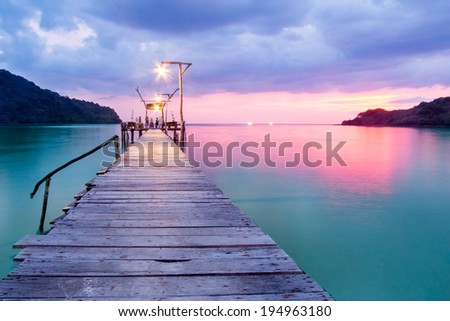 Wooden bridge in the port over sea between sunset