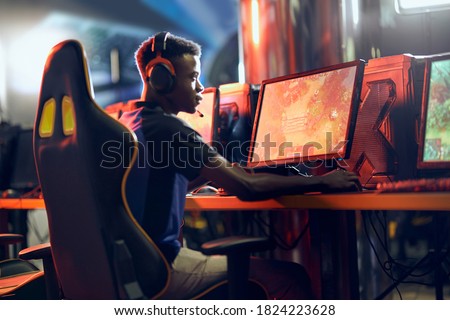 Cybersport concept. Side view of a focused african guy, professional gamer wearing headphones participating in eSport tournament