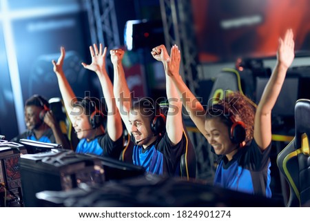 Team of happy professional cyber sport gamers celebrating success while participating in eSports tournament, playing online video games
