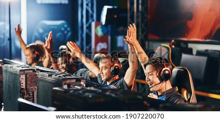 Celebrating success. Team of happy proffesional cyber sport gamers giving high five to each other while participating in eSports tournament