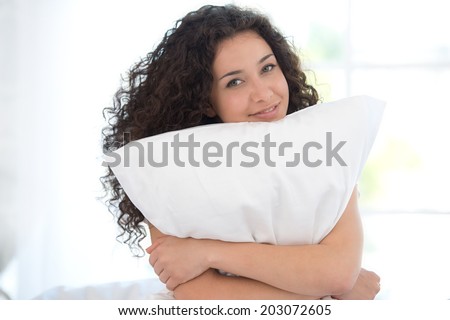 Young woman with the pillow in white bed