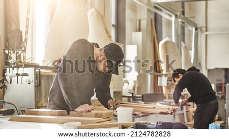 Custom projects with artistic, design oriented value. Portrait of caucasian worker holding a brush, applying varnish paint on a wooden furniture 商業照片 © 