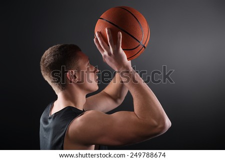 Caucasian young male basketball player free throwing the ball on black background