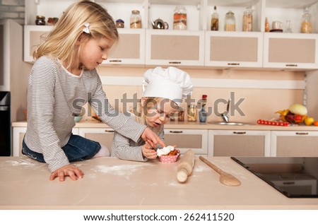 Little cute girls tasting cake. Kitchen interior. Concept for young kitchen hands