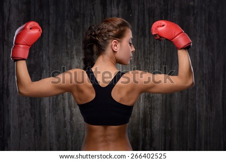 Back view photo of young mixed race sporty woman wearing black tracksuit for training with red boxing gloves. Fitness concept