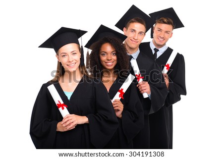 Young students dressed in black graduation gowns. Isolated on white background. Students holding diplomas, smiling and looking at camera