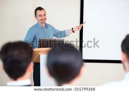 Photo of handsome young businessman making presentation with whiteboard on seminar or meeting to business people