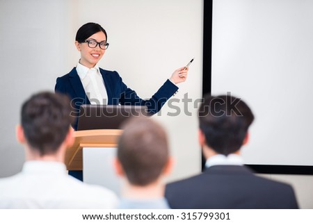 Photo of beautiful young business woman making presentation with whiteboard on seminar or meeting to business people