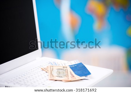 Close up photo of money, tickets and passport with visa on laptop. Travel agency office interior with big world map