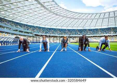 Photo of confident multi ethnic business people lined up getting ready for race on modern sport track. Stadium as a background