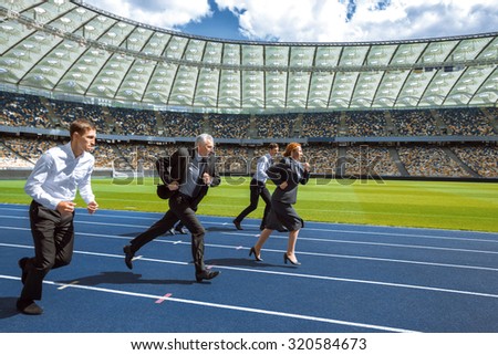 Side view photo of confident multi ethnic business people running to win and cross the finish line on modern sport track. Stadium as a background