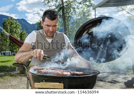 Man at a barbecue grill with smoke