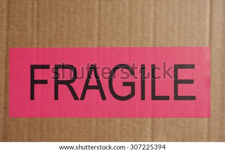 Pink Fragile warning sign label tag on a cardboard box packet parcel for mail post shipping