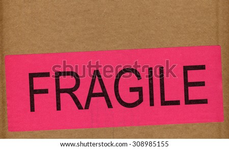 Pink Fragile warning sign label tag on a cardboard box packet parcel for mail post shipping