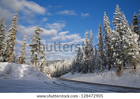 Cascade Mountains, high elevation mountain pass near Canada Border, with October snow fall on road & clear blue sky, near Loup Loup Ski Area, Pacific Northwest, Washington state