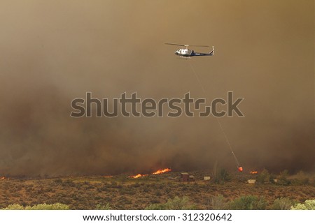 Riverside, WA, USA August 18, 2015: A helicopter finds its way thru heavy smoke as it helps to fight the Okanogan Complex Wild Fire, the largest, most destructive fire in Washington State history