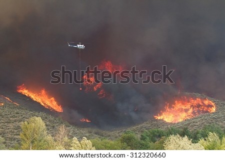 Riverside, WA, USA August 18, 2015: A helicopter finds its way thru smoke and flames as it helps to fight the Okanogan Complex Fire, the largest, most destructive fire in Washington State history