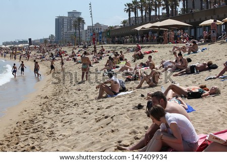 BARCELONA - JUNE 11: Crowded beach with tourists and locals in summer on June 11, 2013 in Barcelona, Spain. Barcelona is a famous destination for hundred of thousands of tourists a year