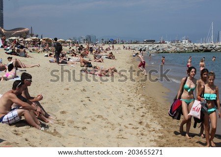 BARCELONA - JUNE 11: Crowded beach with tourists and locals in summer on June 11, 2013 in Barcelona, Spain. Barcelona is a famous destination for hundred of thousands of tourists a year