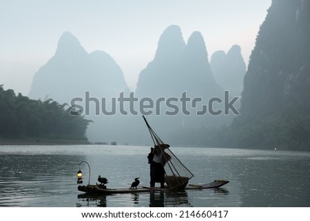 Chinese man fishing with cormorants birds in Yangshuo,  traditional fishing use trained cormorants to fish, China