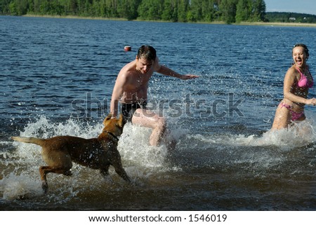 Girl and guy plays with dog in water