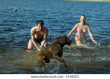 Girl and guy plays with dog in water