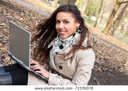 Young smiling girl with a laptop in the park