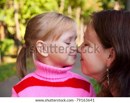 little blond girl smiling portrait with her mother in a profile in the nature