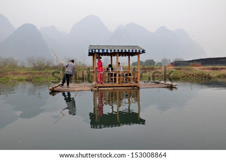 YANGSHUO, CHINA - APRIL 18: Tourists ride on bamboo raft along the river on April 18, 2011 in Yangshuo, China. Yangshou is famous for its fantastic natural mountain and water scenery in the world.