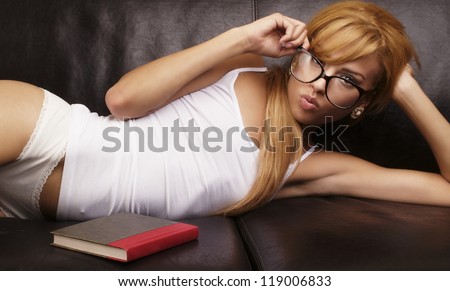 Beautiful young woman lying down on coach with book in sleep wear lingerie.