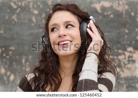 Attractive happy young woman listening to music through head phones.