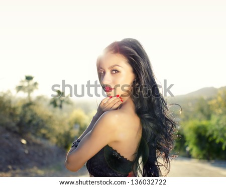 Summer fashion beauty hair portrait,  Beautiful actress model with long dark curly hair posing with sun directly behind her causing sun flare and slight softness......