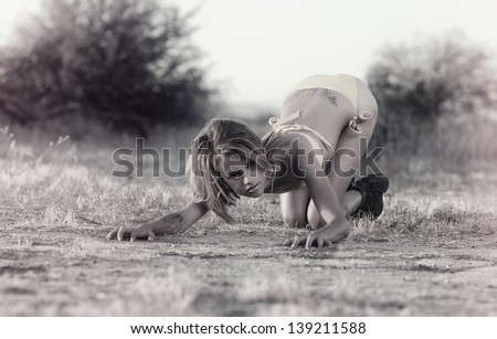 Fashion grunge bikini style.  Wild woman crouching in provocative pose in desert wilderness