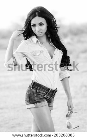 Beautiful exotic young woman wearing denim shorts and top with long dark hair in desert
