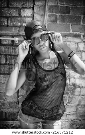 Woman wearing baseball cap, mesh top, sunglasses - city urban vice graffiti wall background