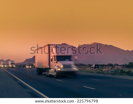 Heavy duty truck lorry traveling on desert highway with mountain background.