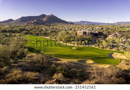 Wide angle high view point of desert golf course landscape community with mountains in background.